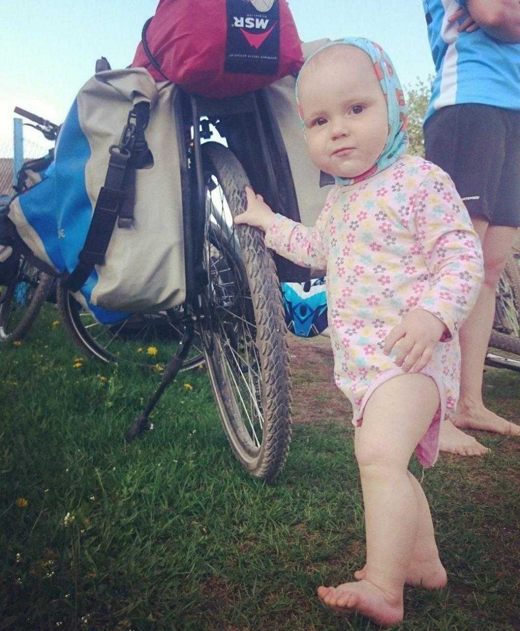 Девочка держит велосипед с помощью отцовского рюкзака