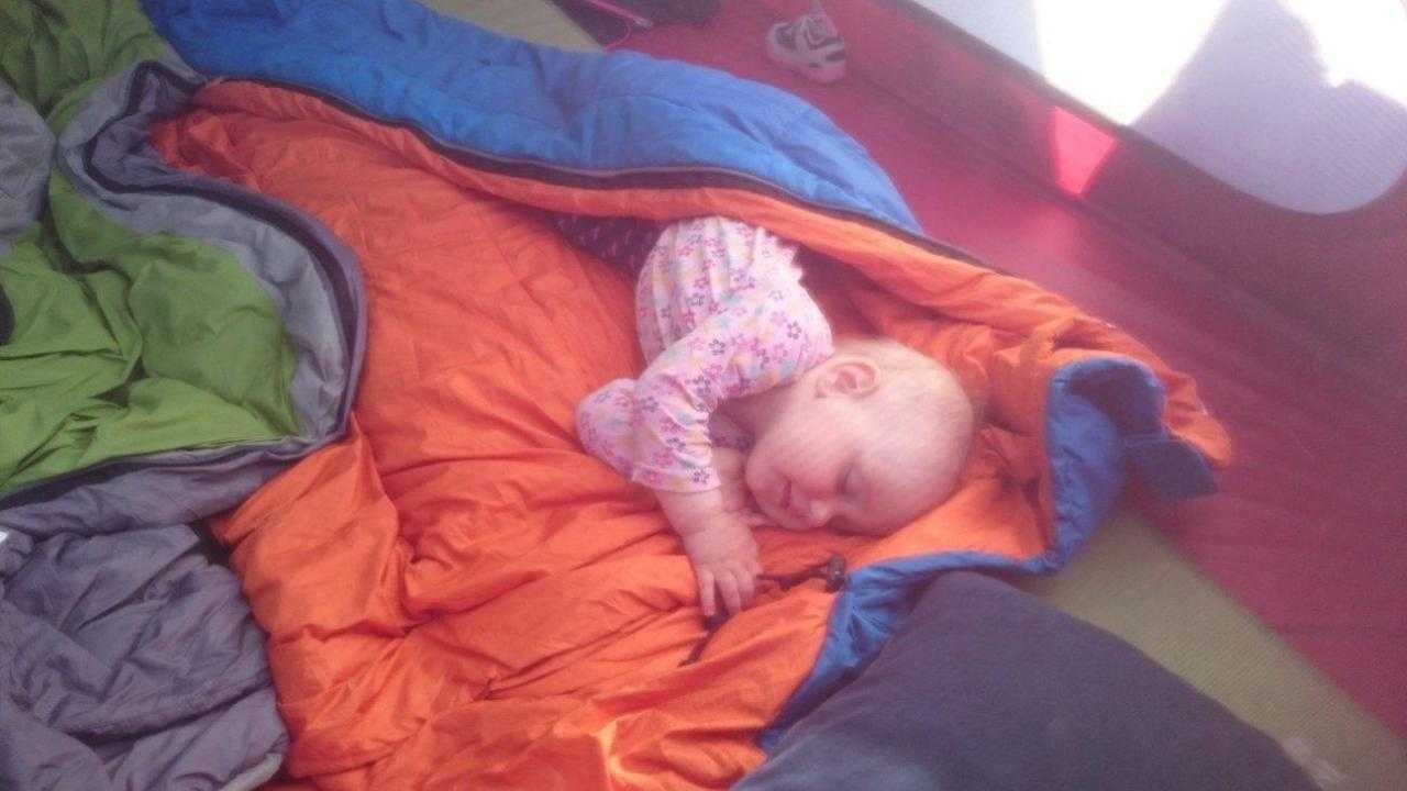 Девушка спит в спальном мешке в палатке