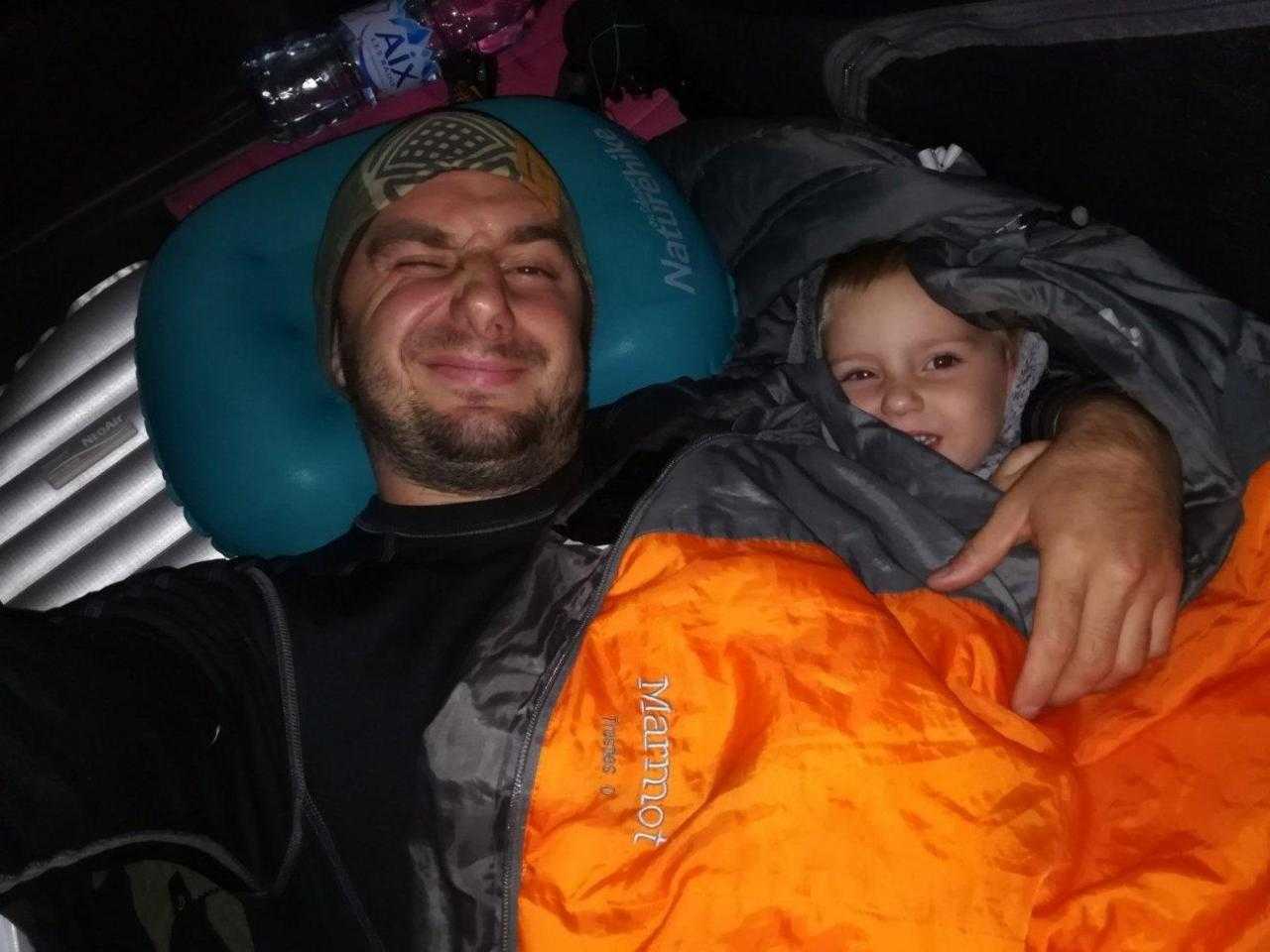 Отец и дочь спят в палатке со спальным мешком